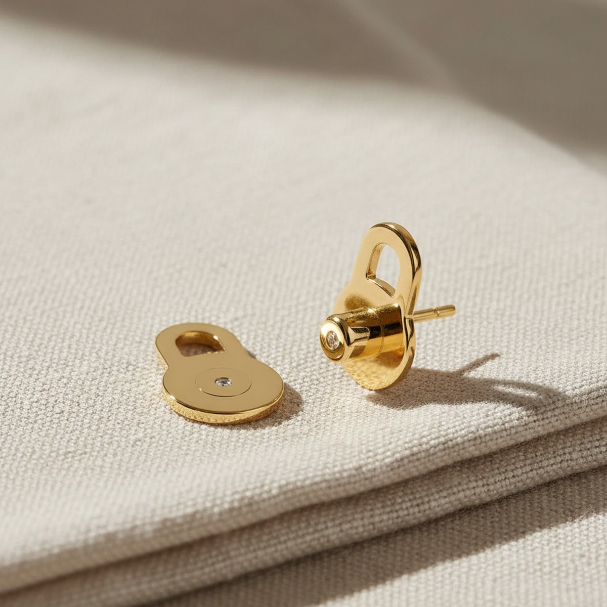 A pair of yellow gold lobe lifters resting on linen