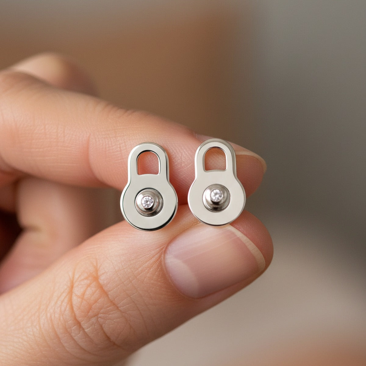 A pair of white gold lobe lifters held between two fingers