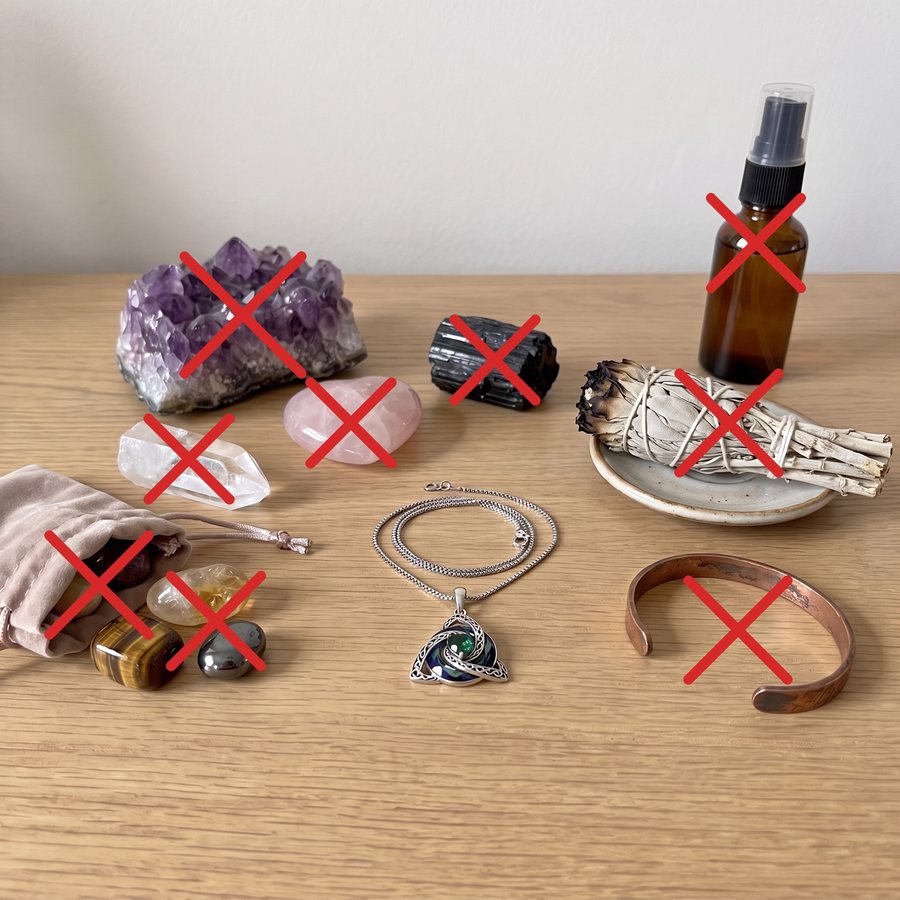 Crystals, sage, a copper bracelet and a spray crossed out around the necklace
