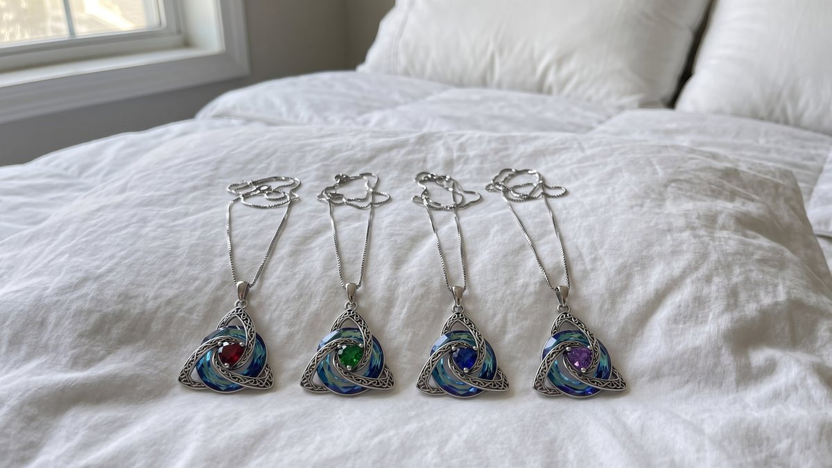 Four witch knot necklaces in four birthstone colours on a bed
