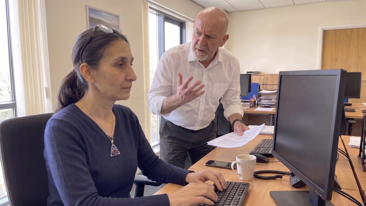 A woman stays calm at her desk while her boss complains