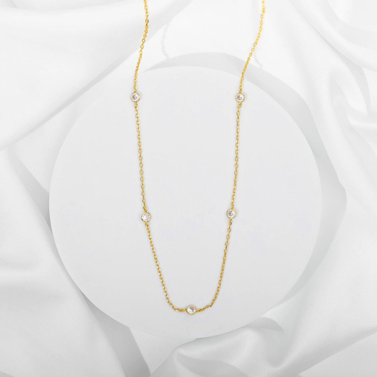 Avera diamond station necklace in yellow gold - flat on silk