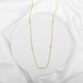 Avera diamond station necklace in yellow gold - flat on silk