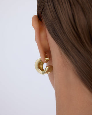 Gold hoop held upright by the lobe lifter, seen from behind