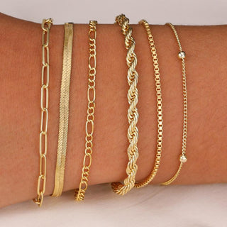 Six gold chain bracelets stacked on the wrist