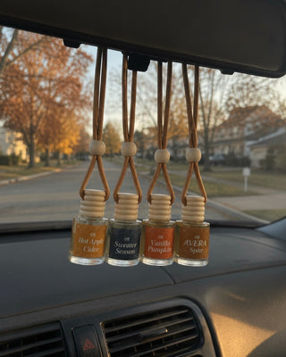 Four Avera car fresheners hanging from a rear-view mirror