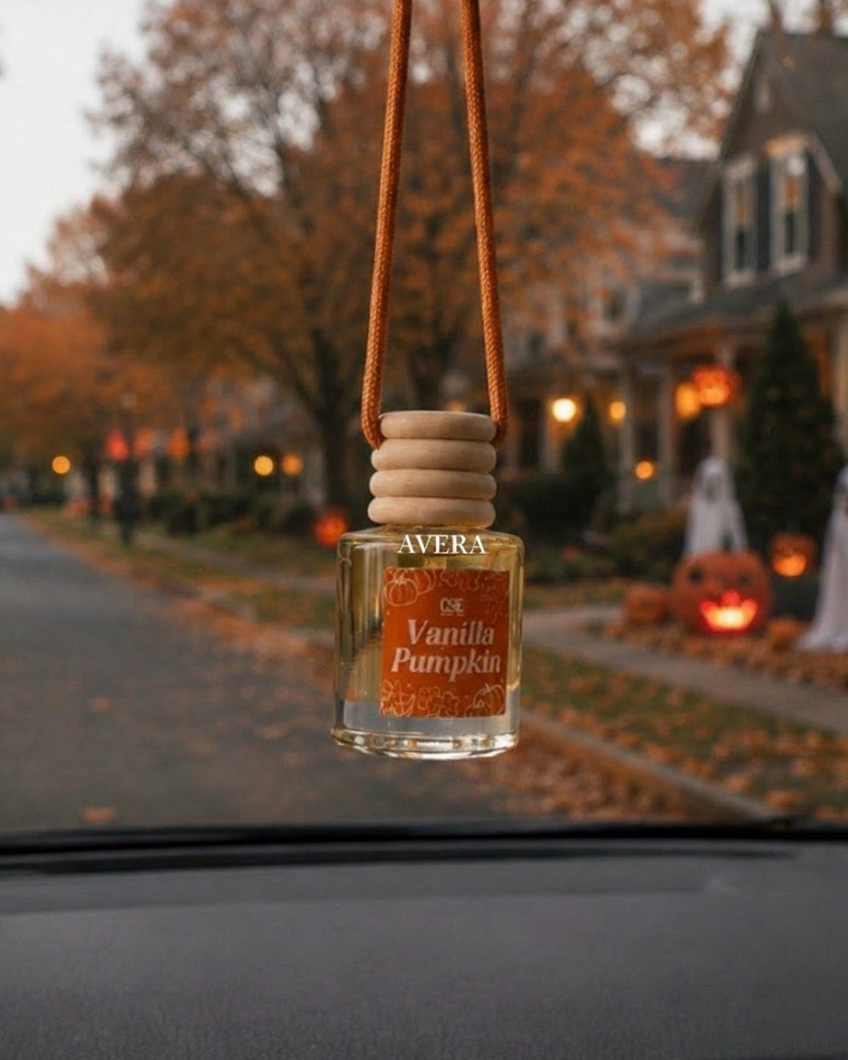 Avera car freshener hanging from a rear-view mirror on an autumn street