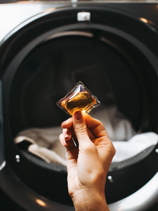 Holding a laundry pod in front of the washer