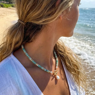 Woman on the beach wearing the Turquoise Bead Pearl Necklace in gold