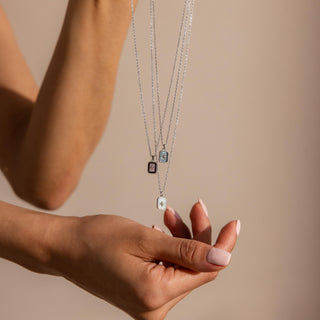 Silver-tone North Star birthstone necklaces held in hand