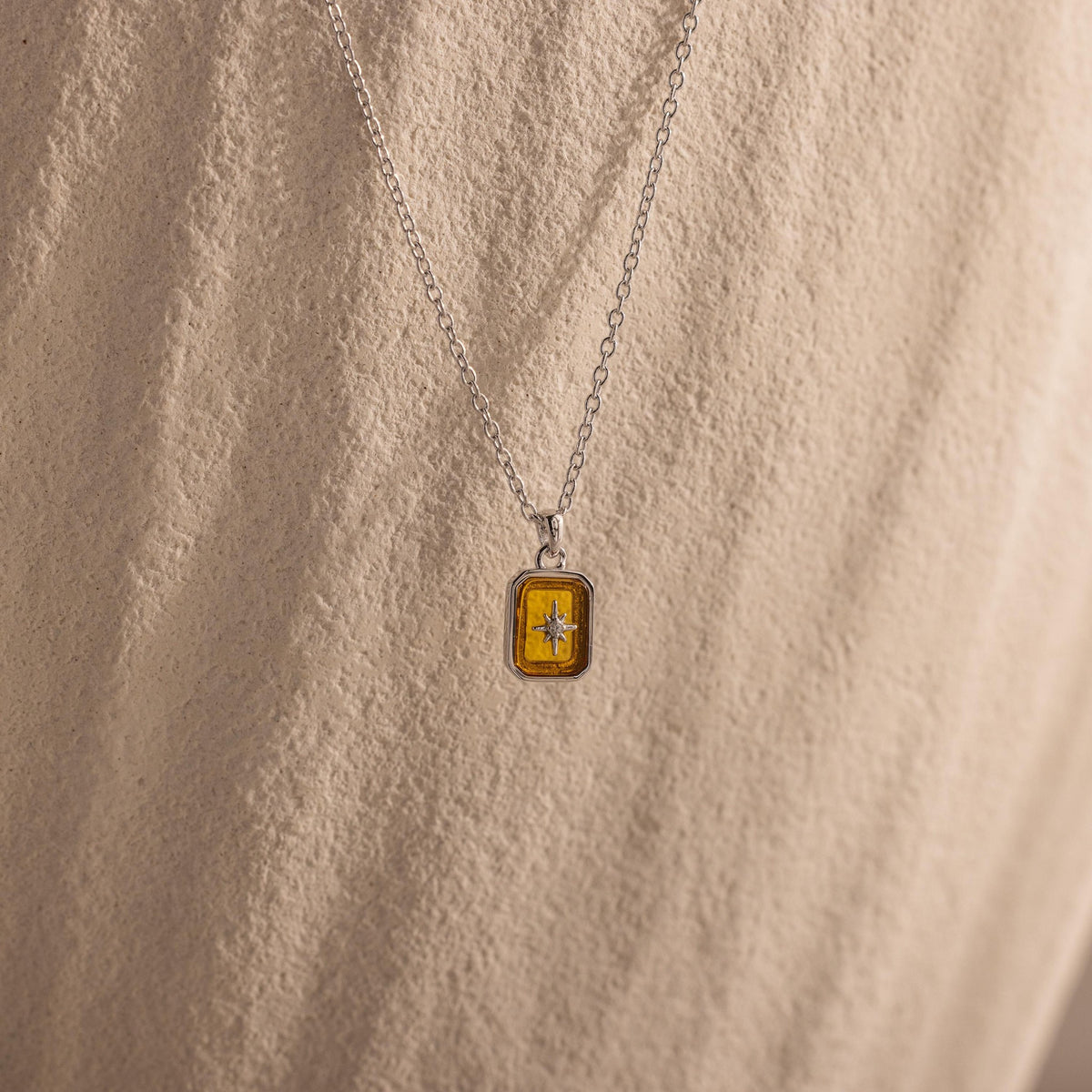 Silver-tone rectangle North Star pendant worn
