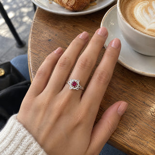 Hand wearing the witch knot birthstone ring on a café table