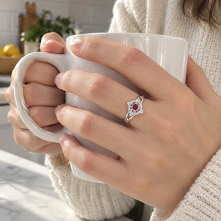 Hands holding a mug, one wearing the witch knot birthstone ring