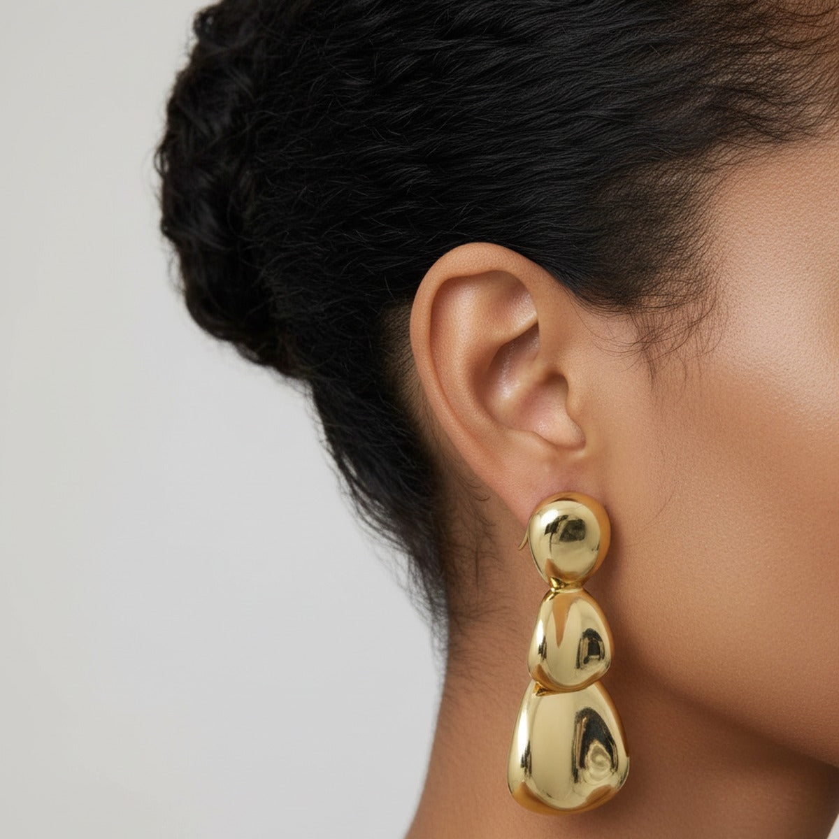 A heavy gold drop earring hanging straight down