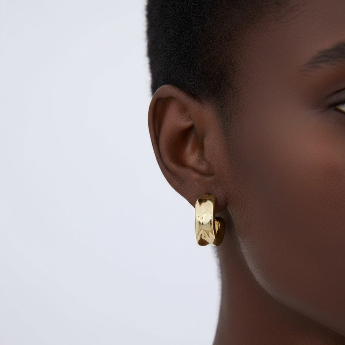 A textured gold huggie hoop squared against the lobe