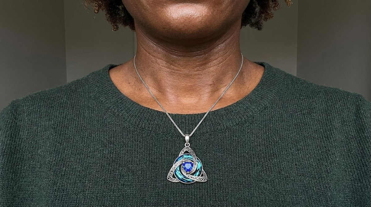 Close-up of the witch knot pendant at the collarbone on a green jumper