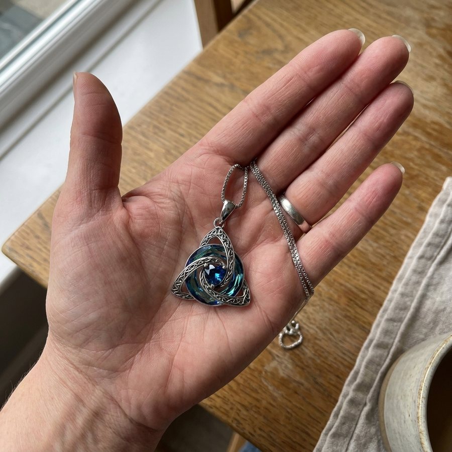 The witch knot pendant resting in an open palm