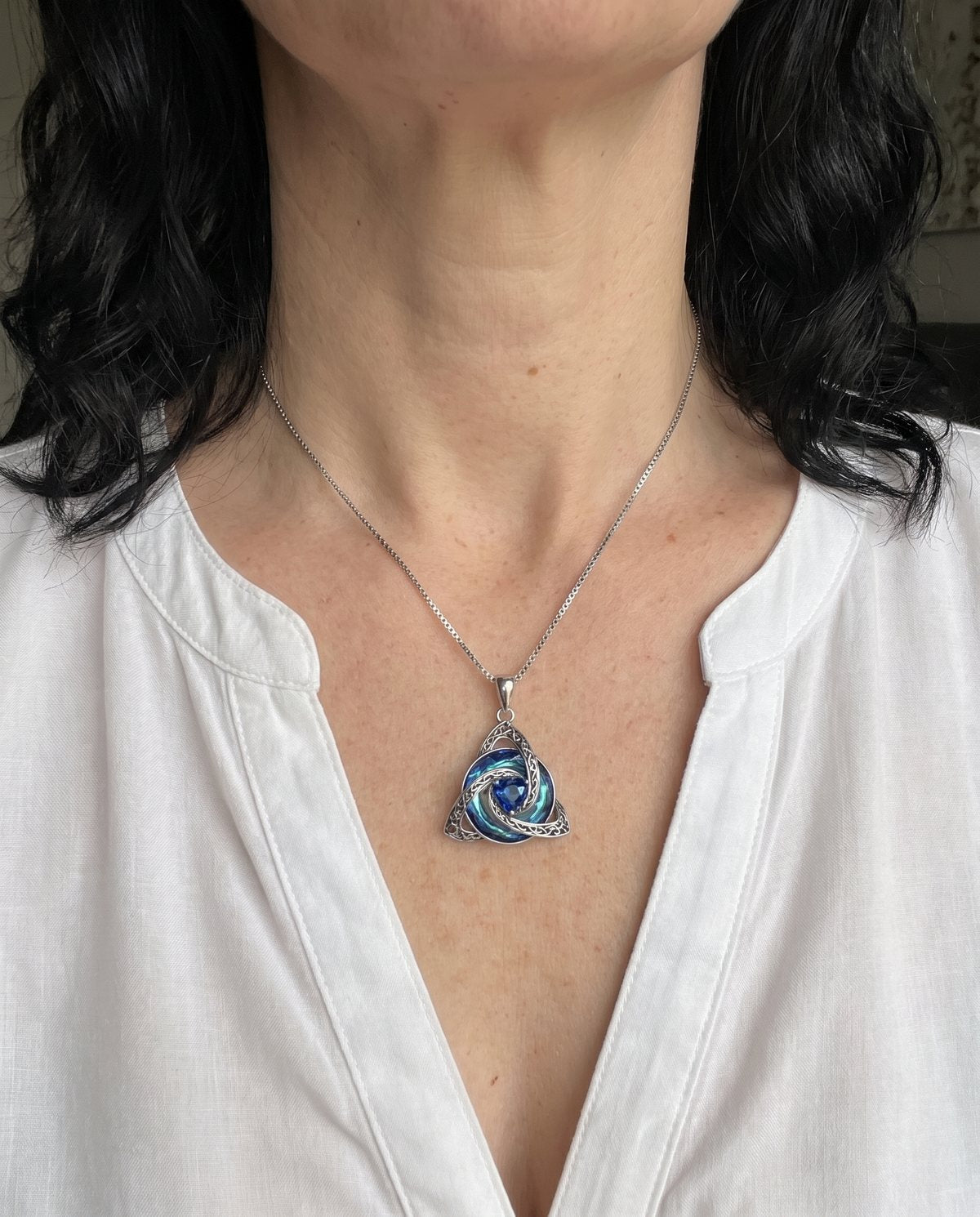 Close-up of the witch knot pendant with a blue heart at the collarbone