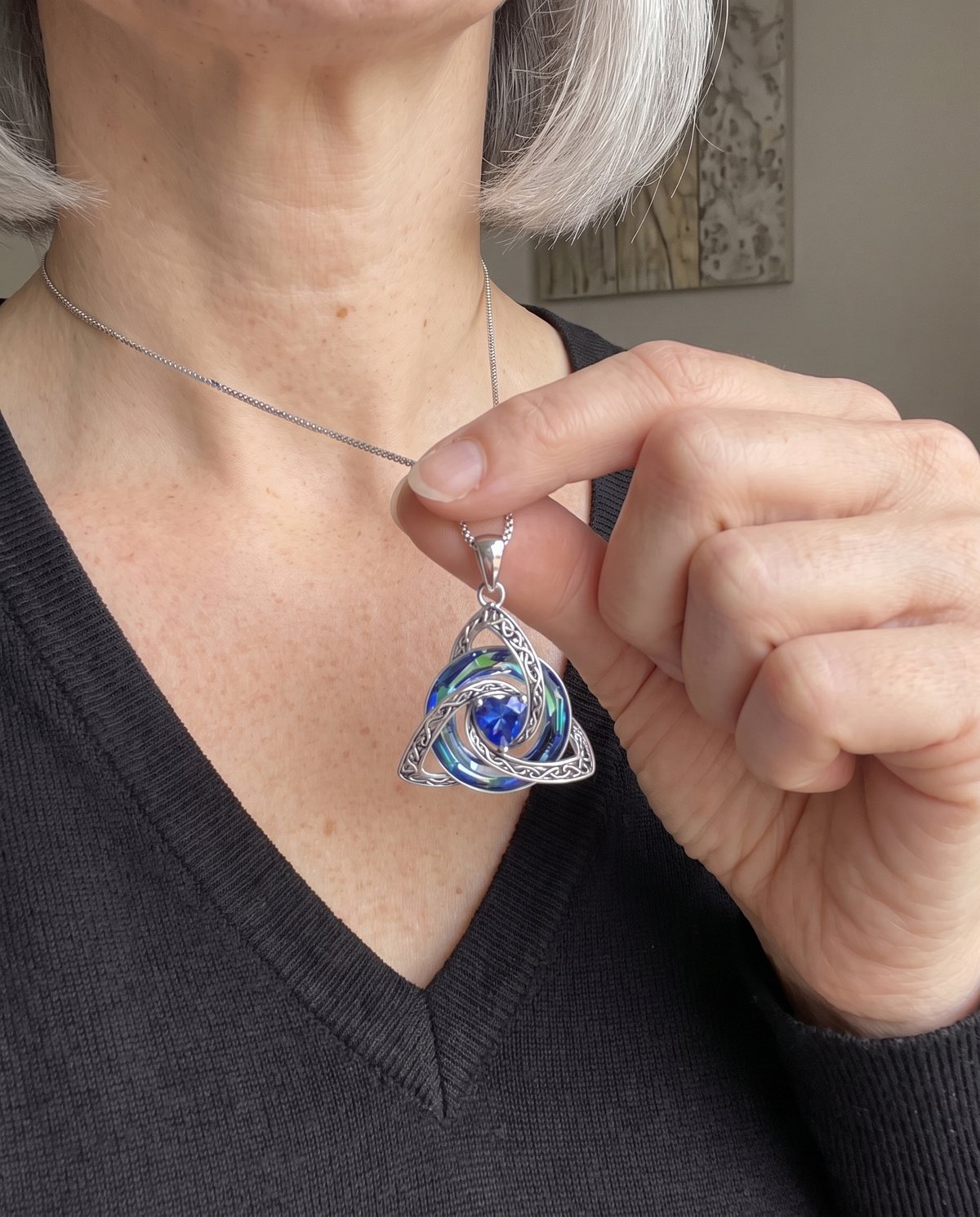 Fingers lifting the pendant to show the sapphire-blue heart